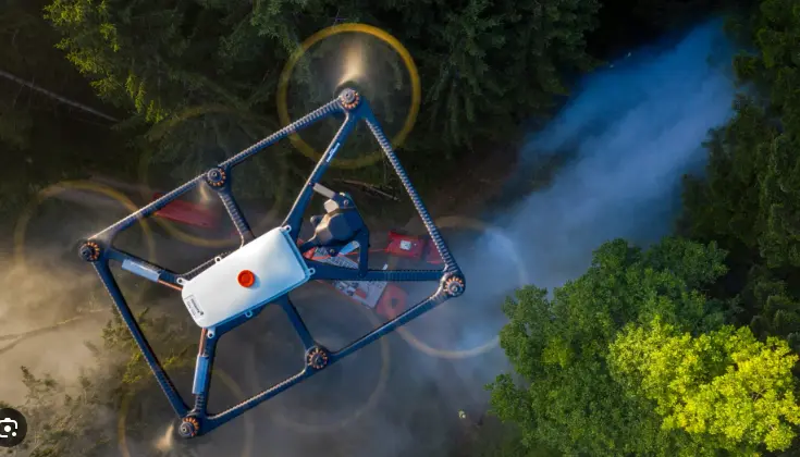 A white drone is hovering above the forest