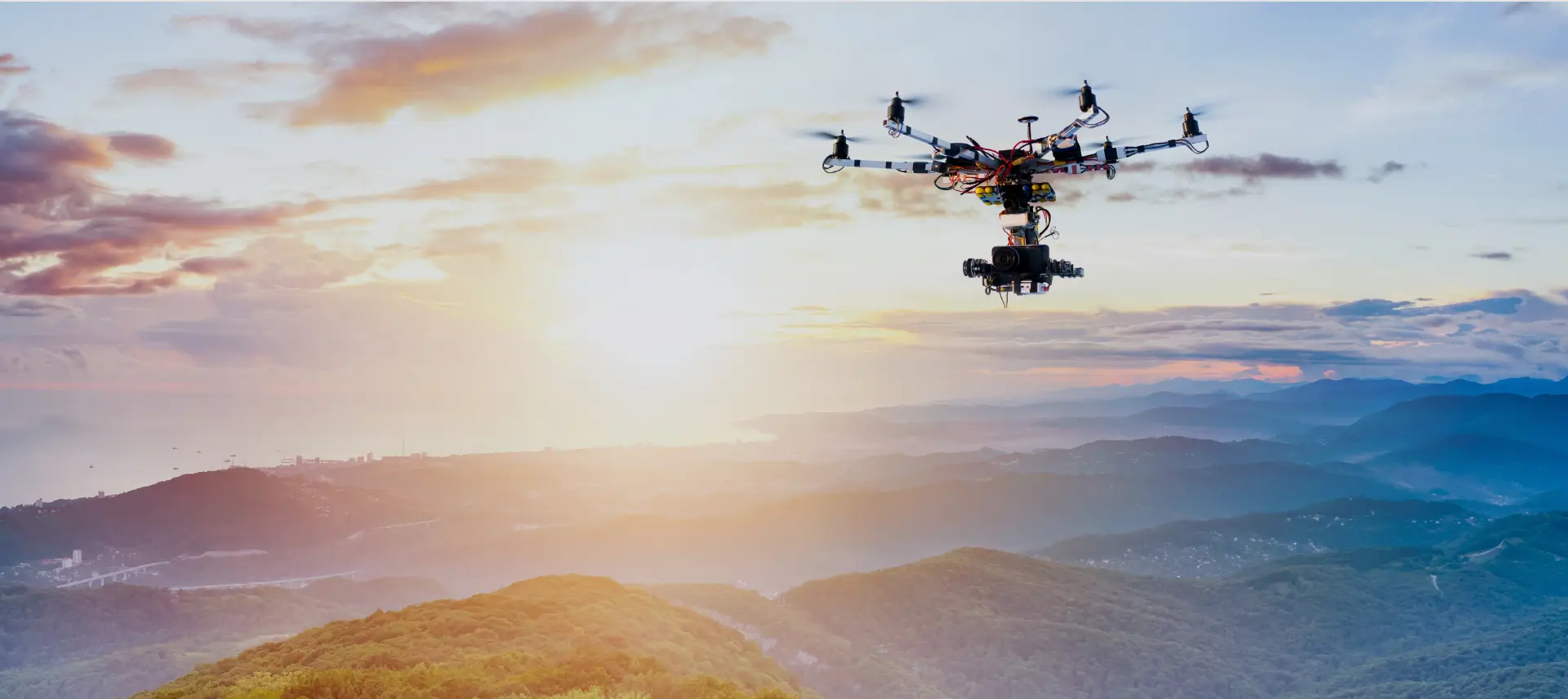 A black camera-equipped drone is hovering in the sky